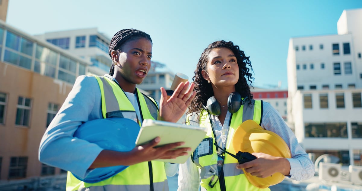 Team of professionals discussing on construction site with tablet
