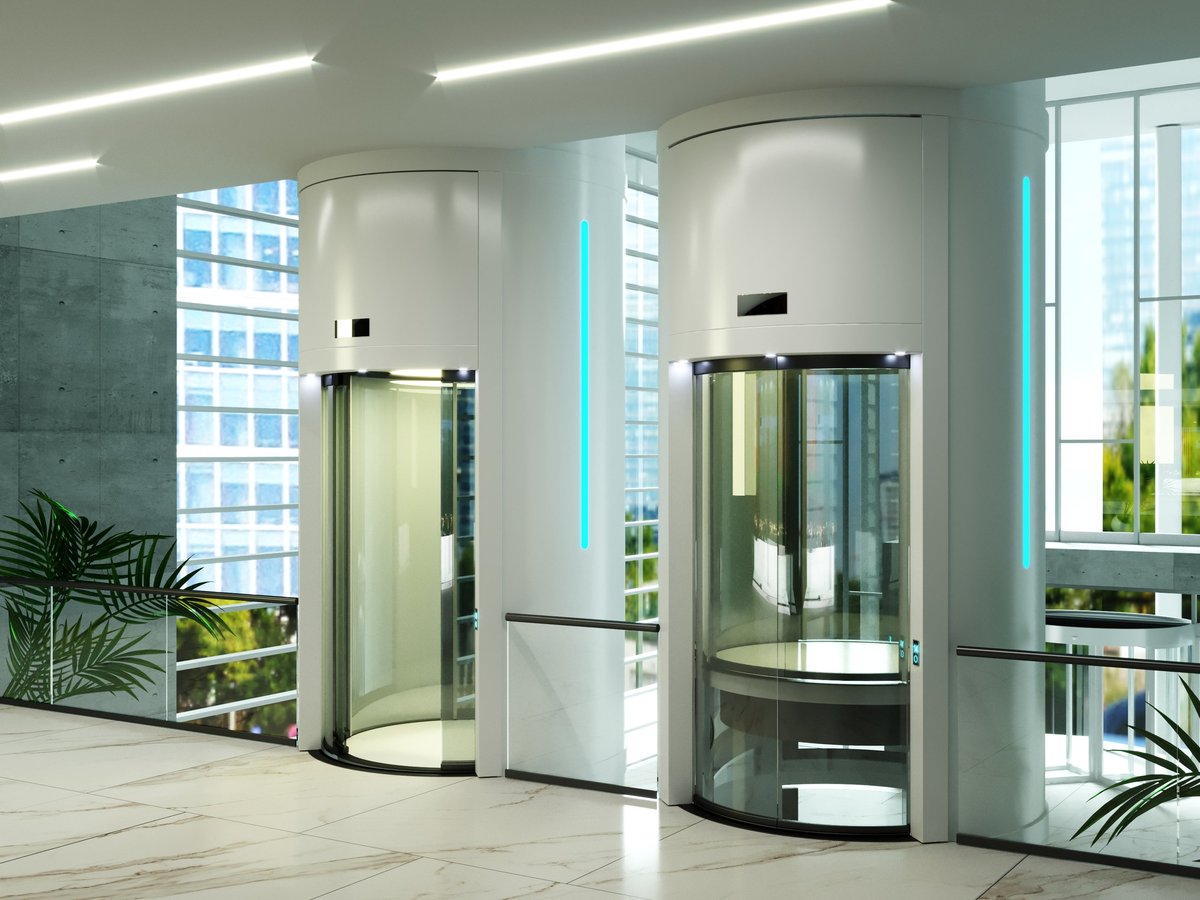 Bright contemporary hall featuring two striking cylindrical glass elevators with gold-colored frames