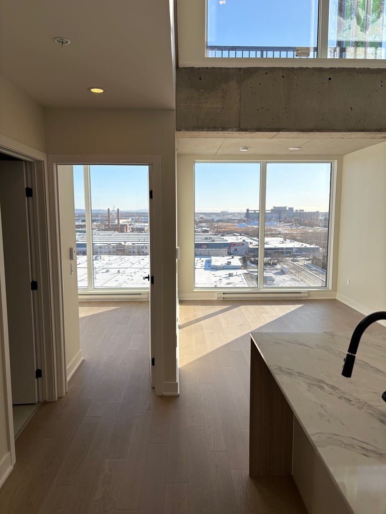 Modern high-rise apartment interior with large windows overlooking city skyline and distant landscape
